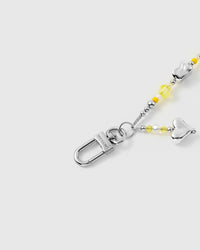 Phone strap with yellow charm beads shown dangling from phone in everyday carry position
