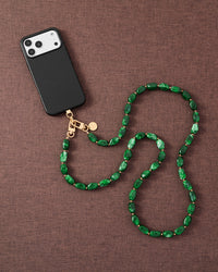 Emerald smoke link phone strap attached to phone on dark brown fabric lifestyle flat-lay