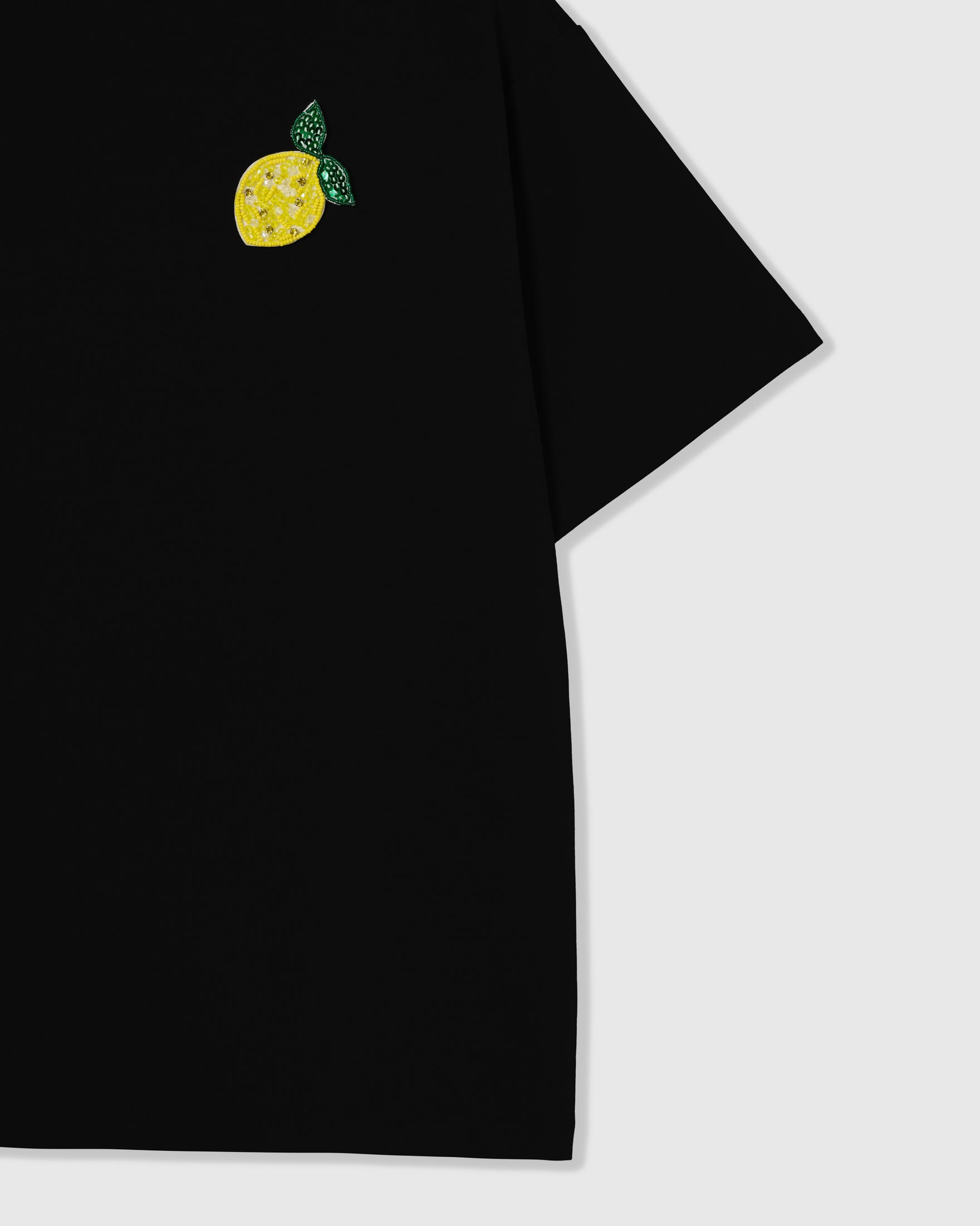 Beaded lemon appliqué on the upper chest of the black oversized boxy Lemon T-Shirt showing the relaxed dropped-shoulder fit