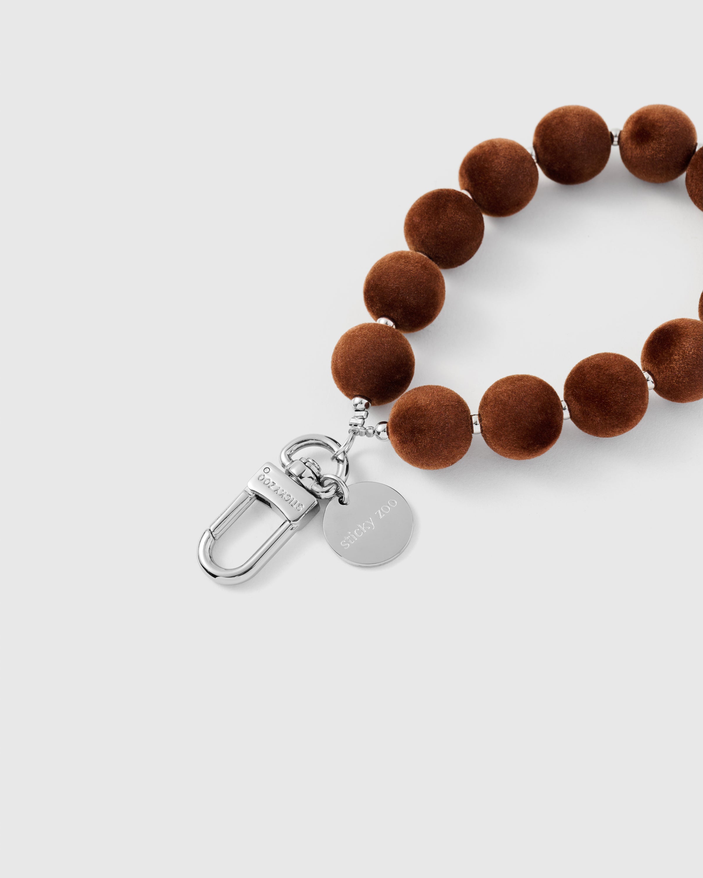 {{Engraved STICKYZOO}} Close-up of silver-tone clasp and engraved STICKYZOO charm disc with velvet pom beads