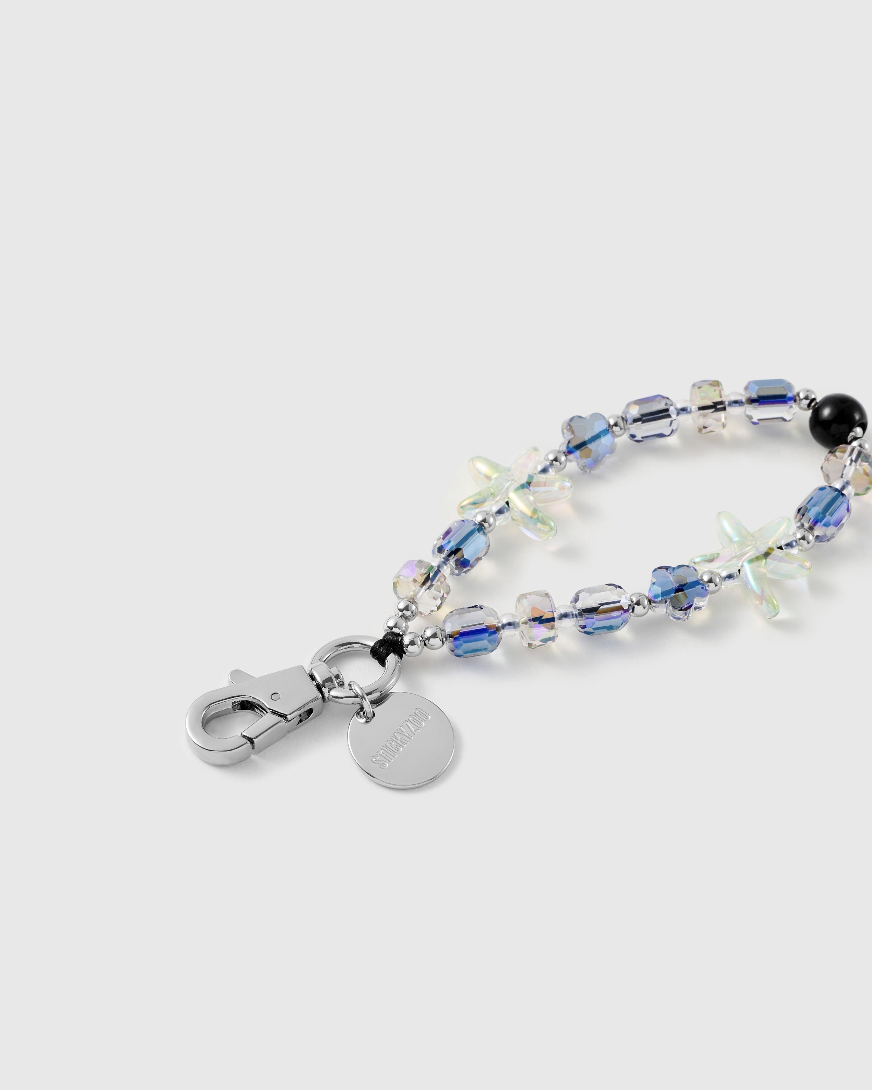 Close-up of the silver-tone lobster clasp, engraved STICKYZOO disc, faceted aurora beads and an iridescent jelly starfish