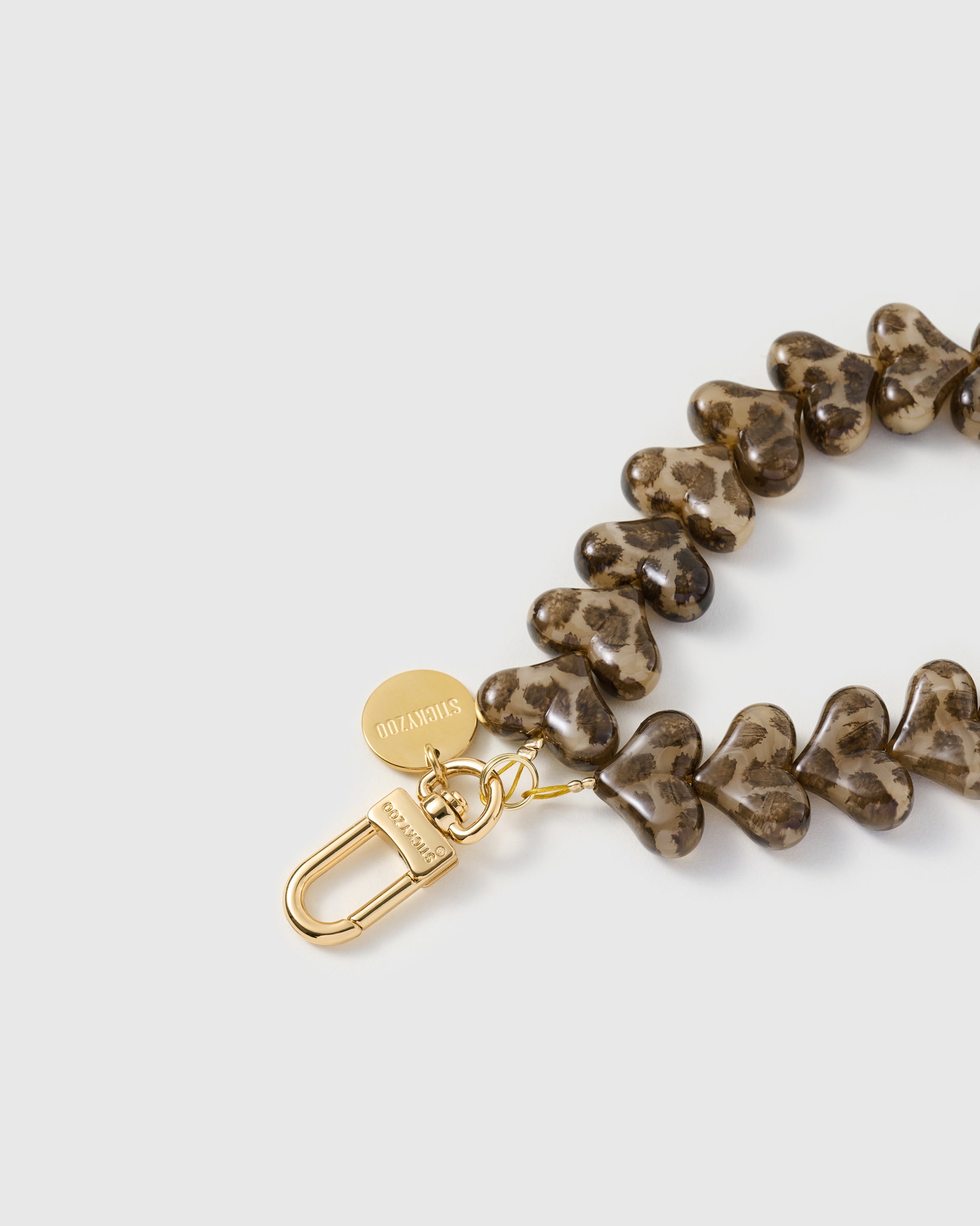 Best Seller close-up of engraved STICKYZOO gold-plated carabiner and heart beads with leopard print pattern set inside the resin