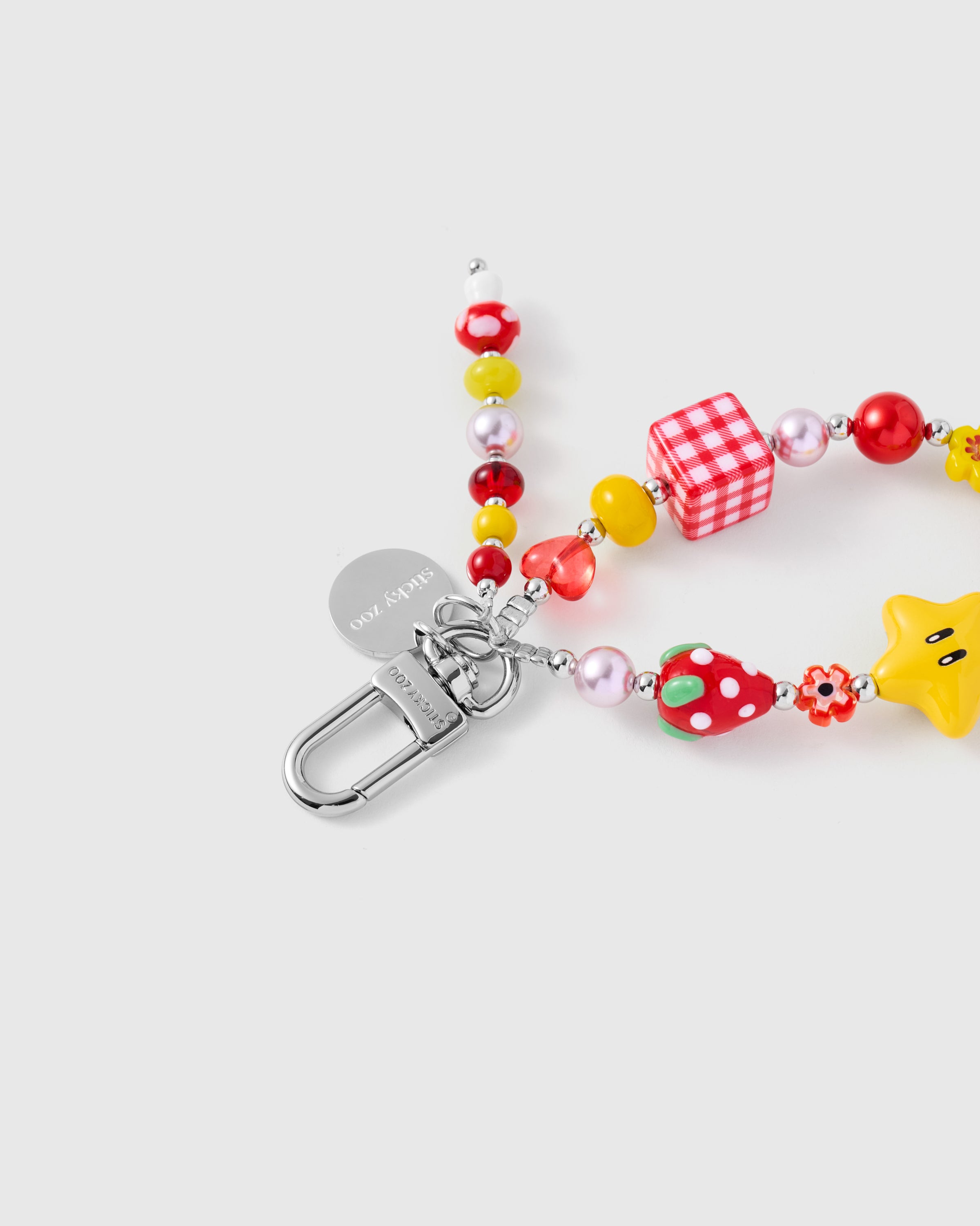 {{Engraved STICKYZOO}} Close-up of silver-tone clasp and engraved STICKYZOO disc with red gingham cube and star beads