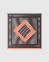 Op-art diamond silk scarf knotted in a bow showing the charcoal field with ivory stripes and terracotta border by STICKYZOO