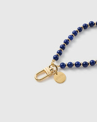 Close-up of the 18K gold-plated hook, engraved STICKYZOO disc and deep cobalt-blue stone beads — each one unique
