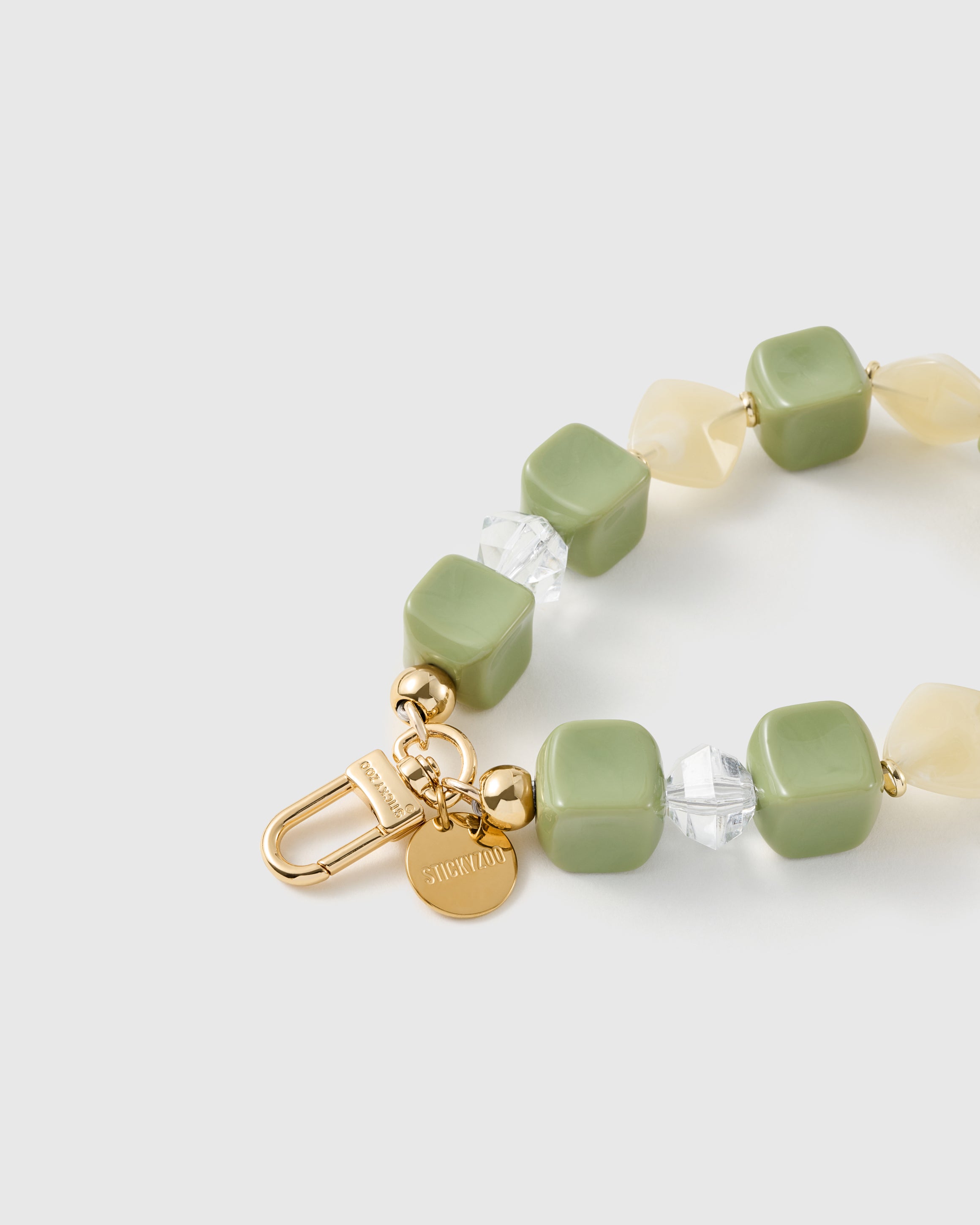 Close-up of the 18K gold-plated hook, engraved STICKYZOO disc and matcha marbled beads — no two alike