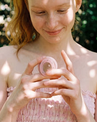 Person holding the pink mirror pop-grip from the STICKYZOO lavender butterfly phone case in soft daylight