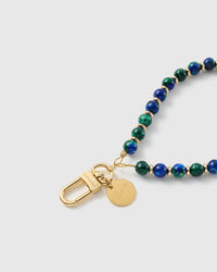 Close-up of the 18K gold-plated hook, engraved STICKYZOO disc and blue-and-green stone beads — each one unique