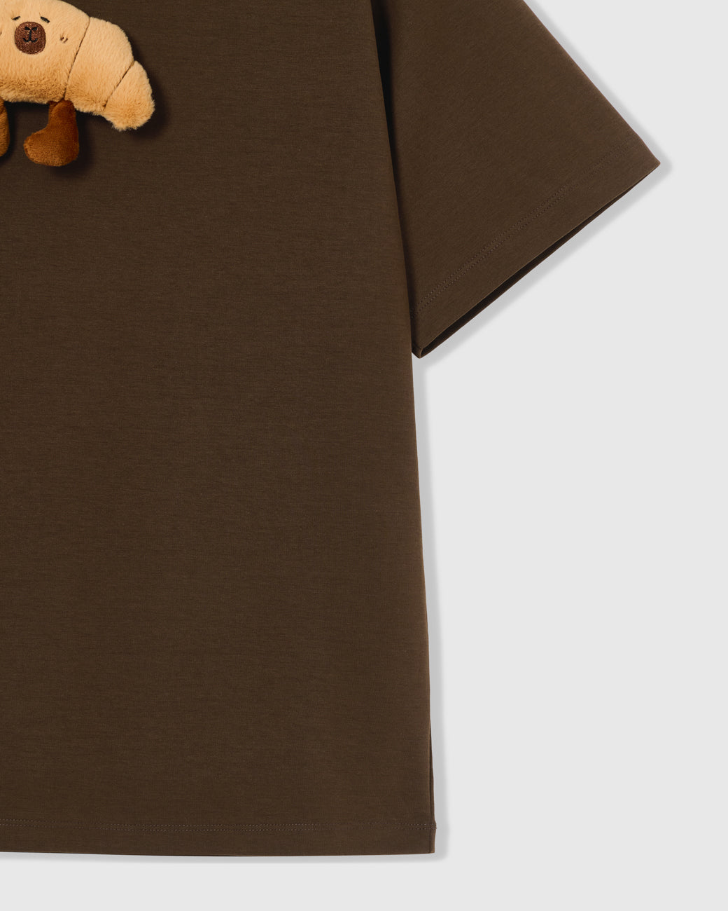 Detail of hem and fabric on STICKYZOO brown Runaway Croissant T-Shirt showing premium cotton weight
