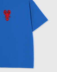 Styled layflat of the blue STICKYZOO Lobster T-Shirt showing the beaded lobster applique and the relaxed dropped-shoulder drape.