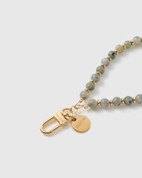 Macro of the 18K gold-plated clasp and engraved STICKYZOO charm disc on the sage grey-green stone strap.
