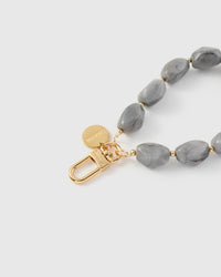 Close-up of gold-plated clasp and engraved STICKYZOO charm disc with grey marble stone beads