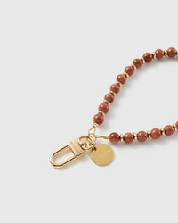 Macro of the 18K gold-plated clasp and engraved STICKYZOO charm disc on the copper goldstone strap
