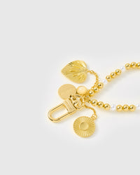 Close-up of engraved STICKYZOO clasp with gold beads, shell-heart charm, and sun medallion