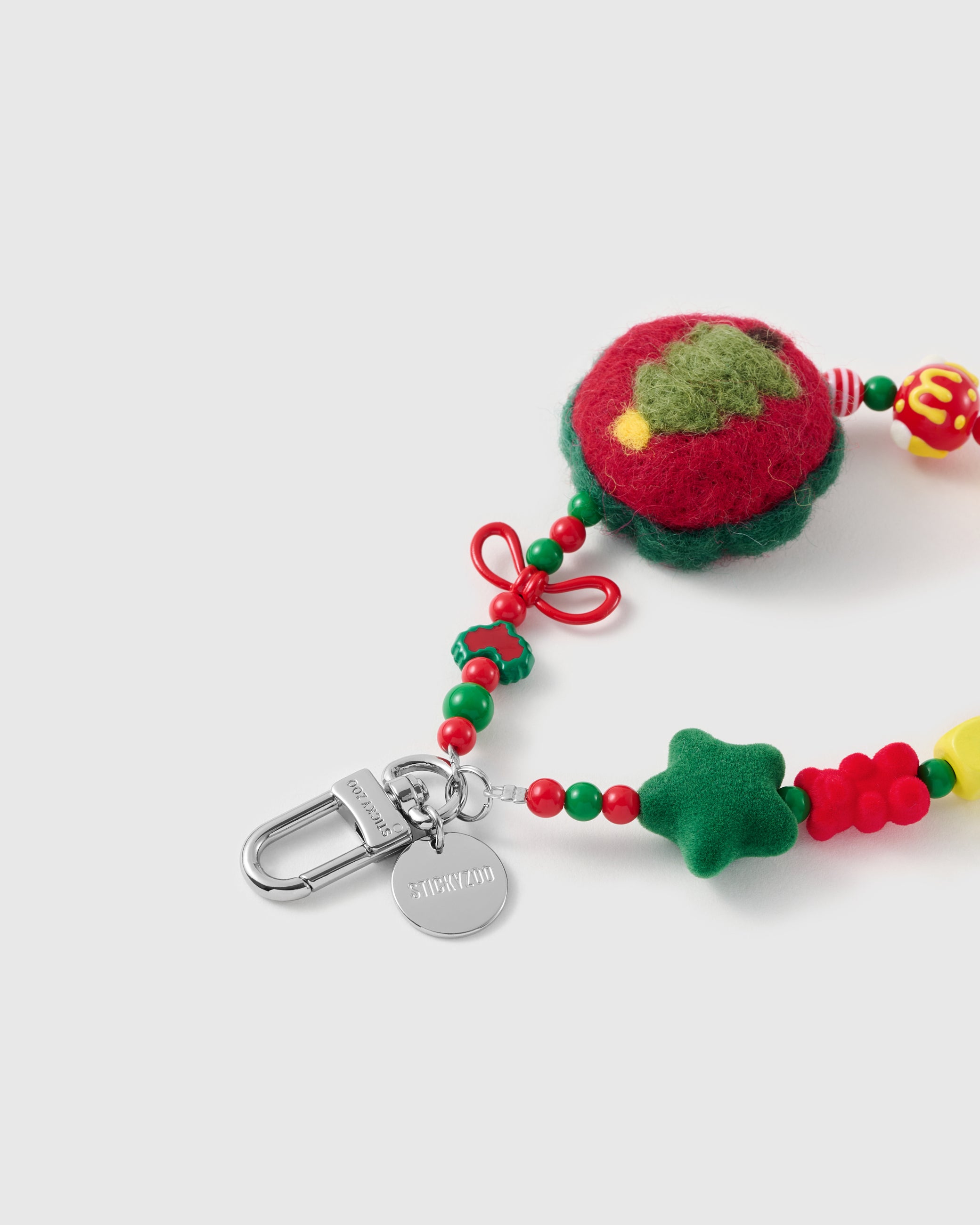 Close-up of the silver-tone hook, engraved STICKYZOO disc and the felted tree charm, wire bow, flocked star and glossy holiday beads — soft and tactile