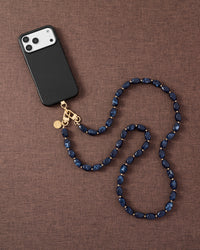 Midnight smoke link phone strap attached to phone on dark brown fabric lifestyle flat-lay