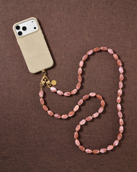 Dusty-rose beaded cross-body phone strap styled on fabric, handmade not factory