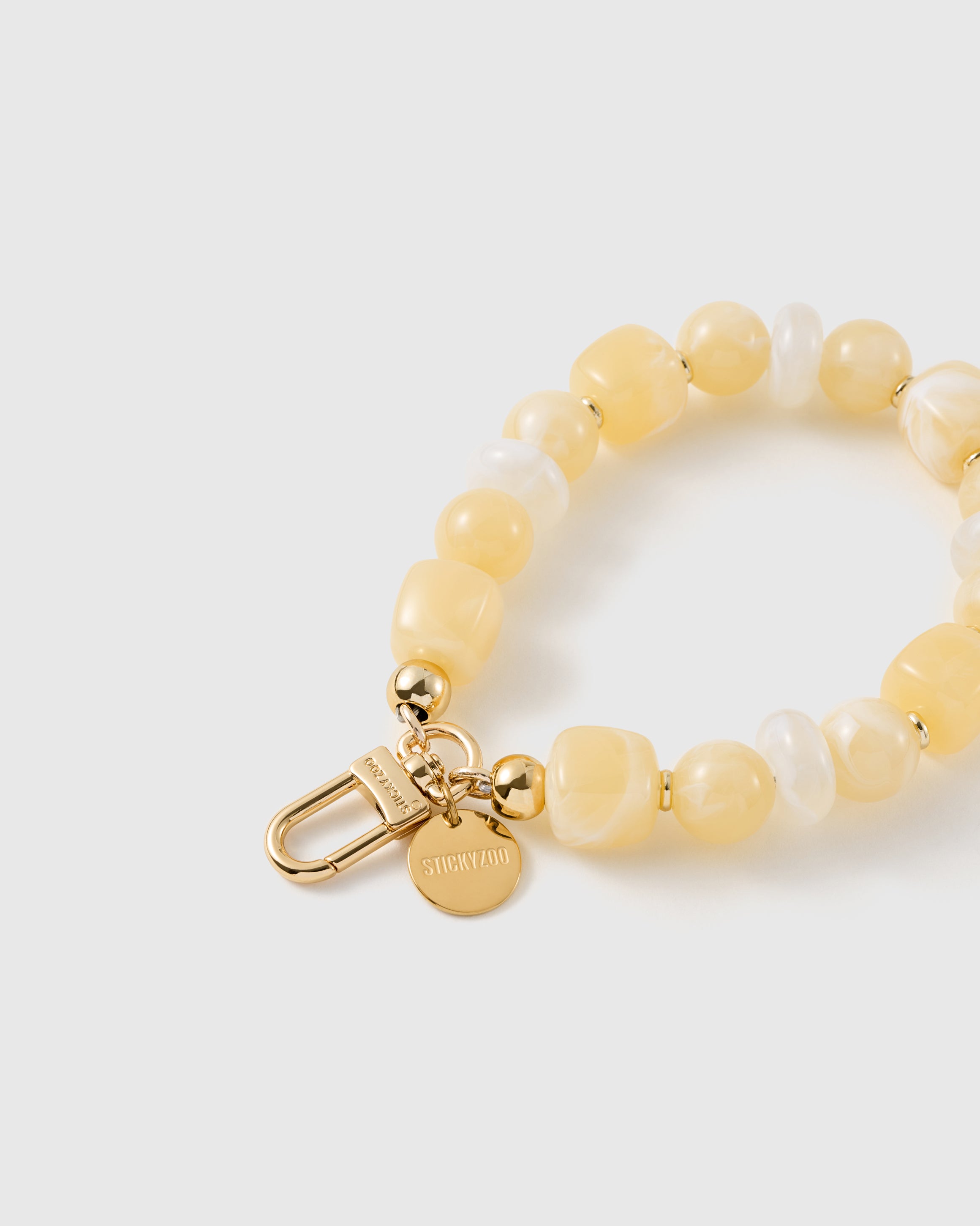 Close-up of the 18K gold-plated hook, engraved STICKYZOO disc and buttermilk beads — every one different