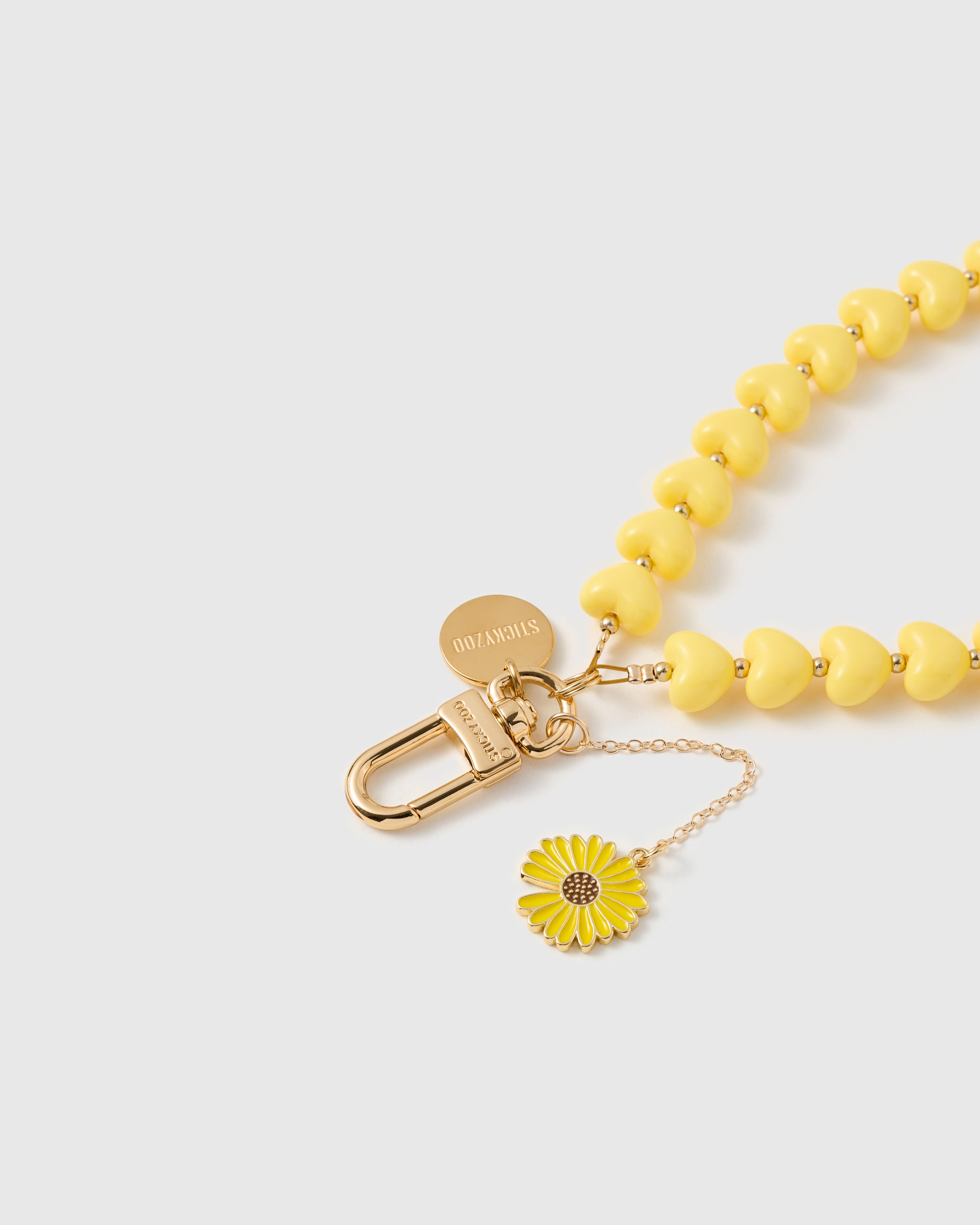 Close-up of 18K gold-plated carabiner and engraved STICKYZOO disc on lemon heart bead strand