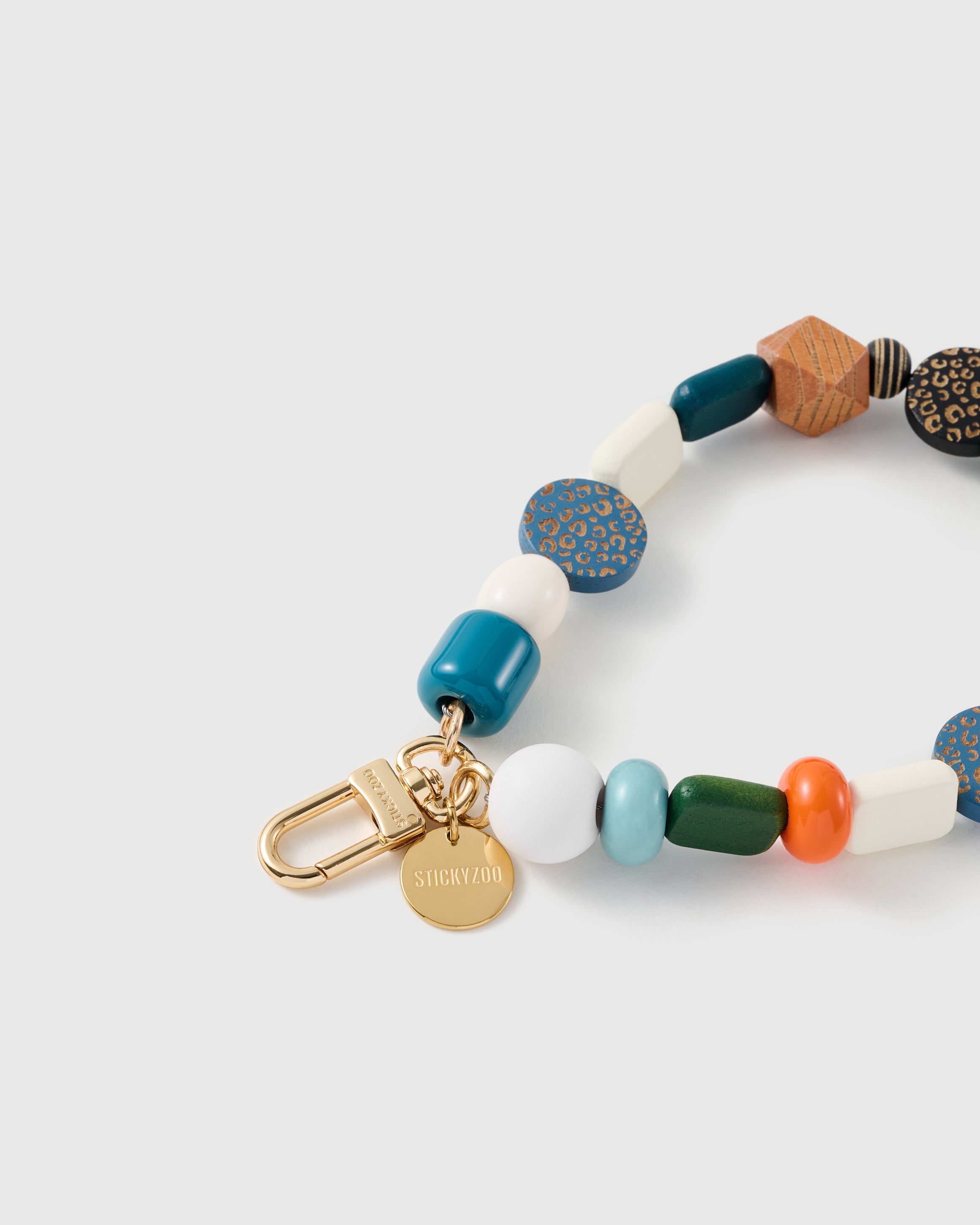 Close-up of the 18K gold-plated hook, engraved STICKYZOO disc and mixed wood and glossy beads — every one different