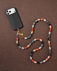 Warm-toned resin bead cross-body strap styled in a flat-lay on soft fabric, handmade not factory.
