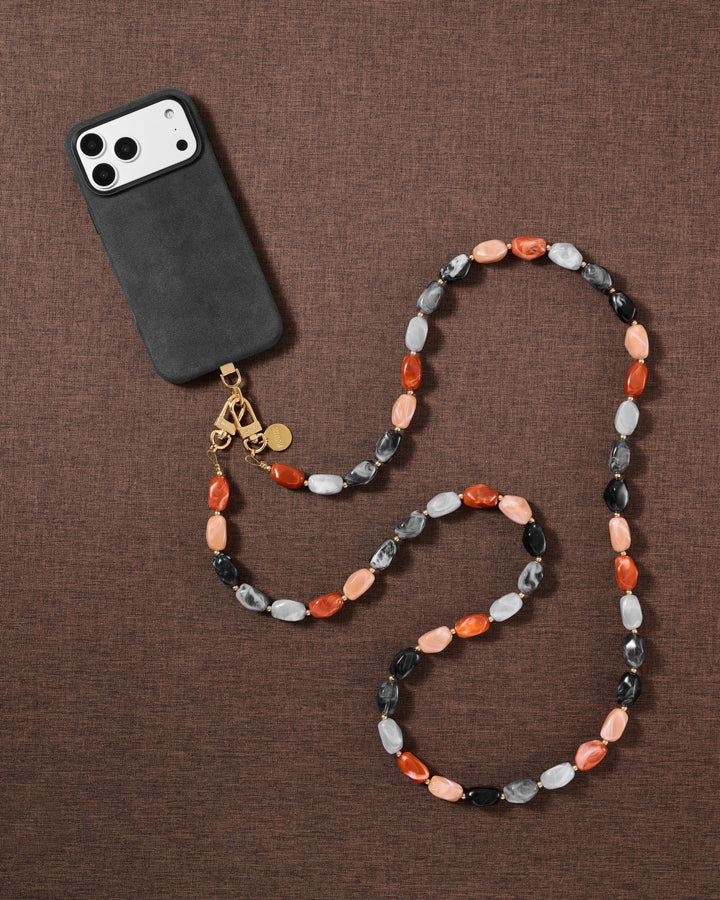 Warm-toned resin bead cross-body strap styled in a flat-lay on soft fabric, handmade not factory.