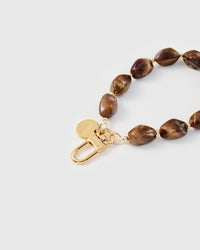 Close-up of gold-plated clasp and engraved STICKYZOO charm disc with dark amber stone beads