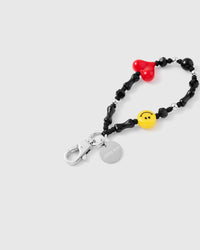 Close-up of black heart charm and yellow smiley bead with white tube beads and faceted crystals