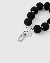 Black plush phone strap hanging from phone showing statement wrist carry