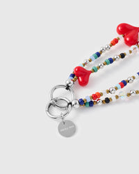 Close-up of silver-tone ring clasp and engraved charm disc with red glass hearts and seed beads