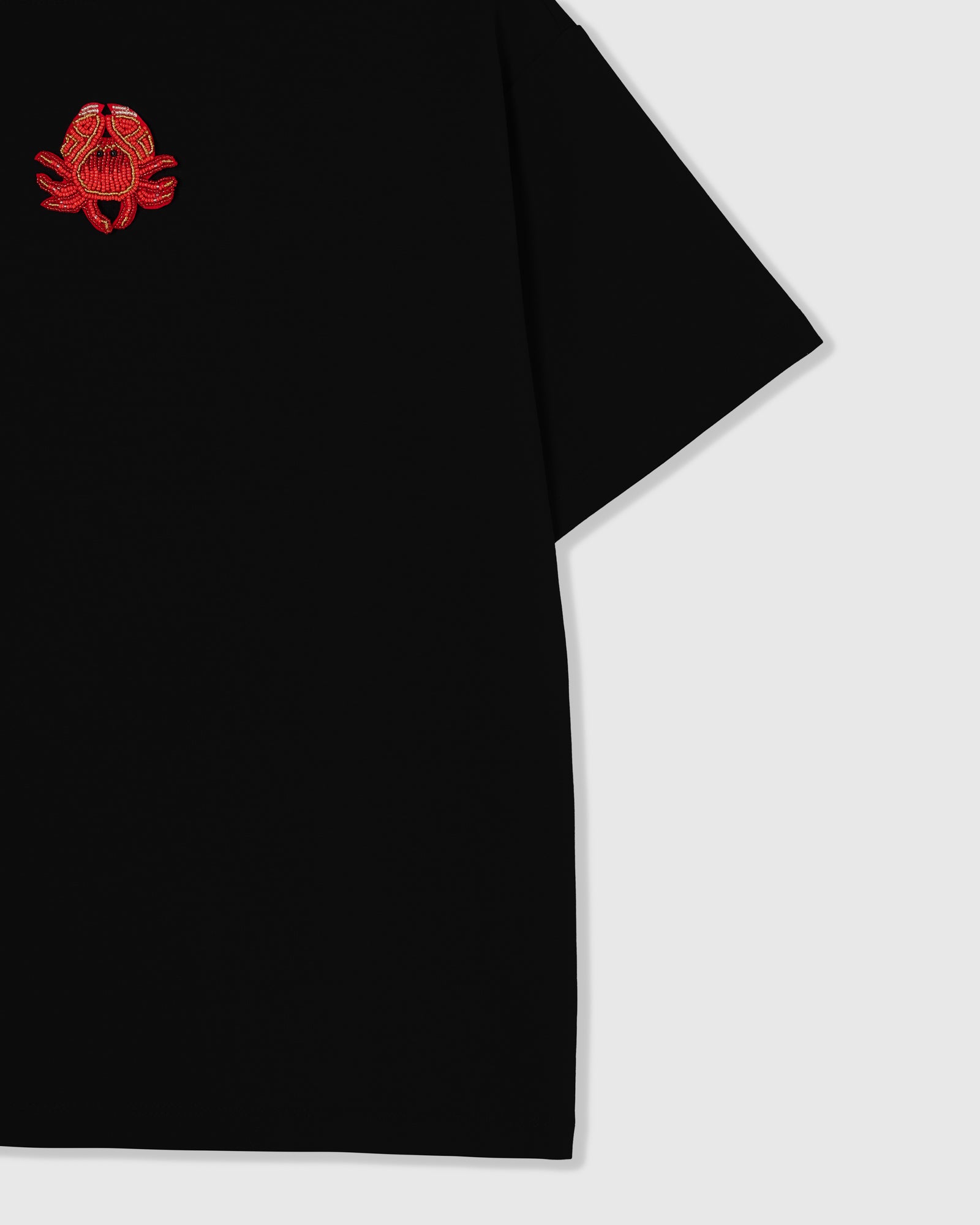 Styled layflat of the black STICKYZOO Crab T-Shirt showing the beaded crab applique and the relaxed dropped-shoulder drape.