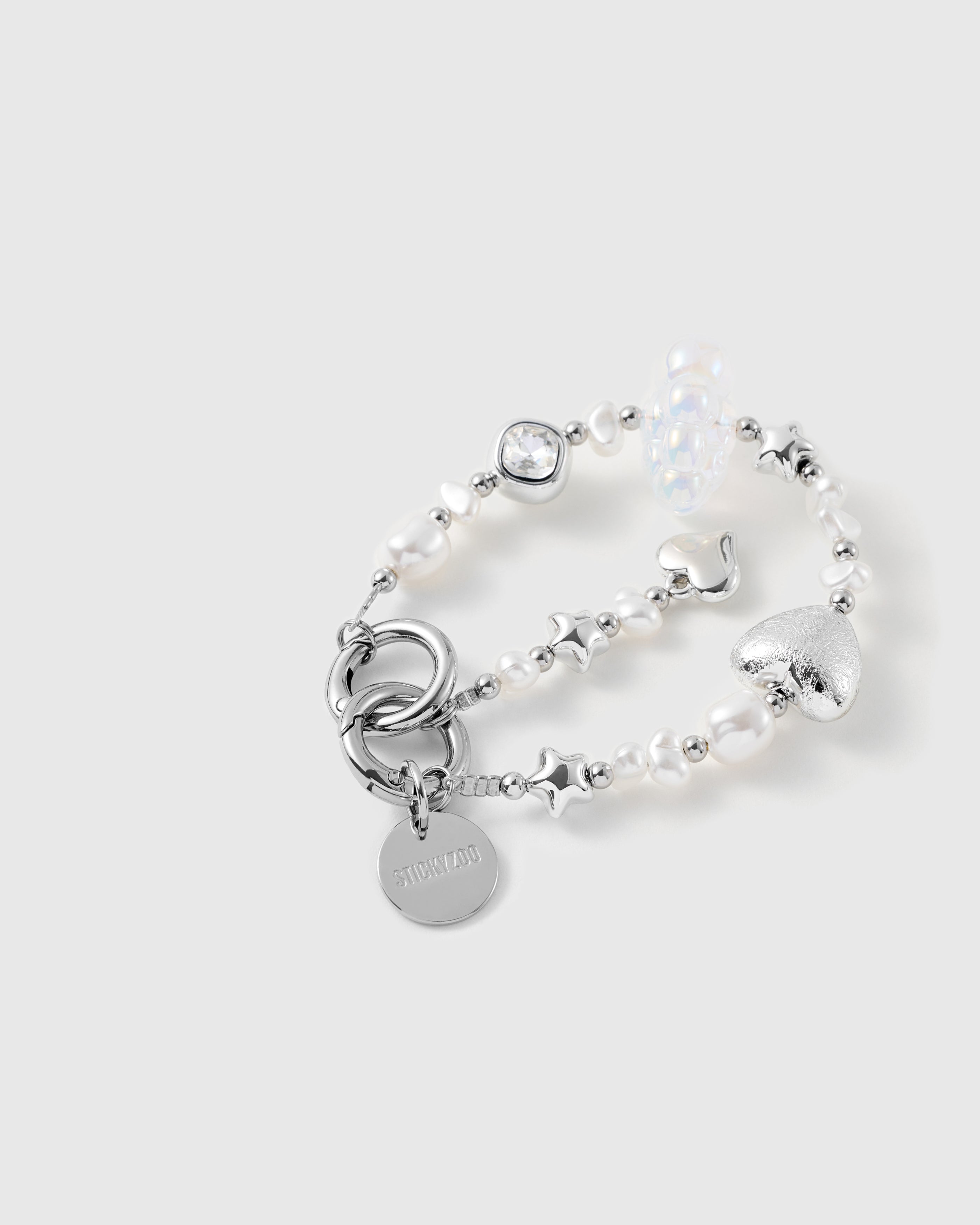Close-up of the beaded strap: foil-textured silver heart, faceted clear gem in a silver bezel, silver stars and iridescent cloud bead among pearls