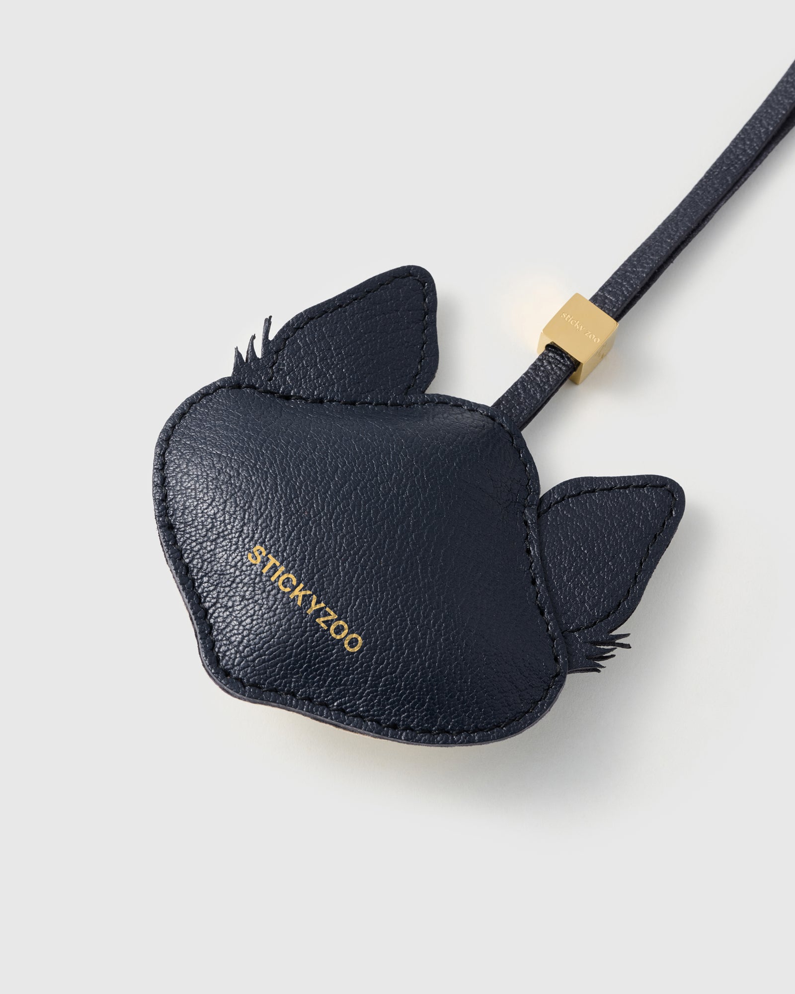 {{Gold debossed STICKYZOO}} Back panel of husky charm in deep navy French Alran leather with gold debossed STICKYZOO branding