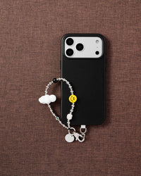 Phone with Frost Cloud Smile strap on brown fabric lifestyle flat-lay