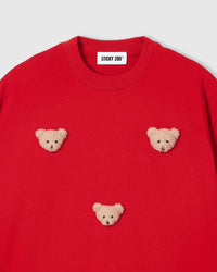 Close-up of plush bear face appliques on red 230gsm cotton showing fuzzy 3D texture and embroidered features