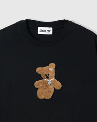 Close-up of plush bear applique on black cotton showing bold contrast and dimensional texture