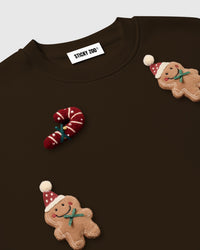 Close-up detail of plush gingerbread man with Santa hat and candy cane appliques showing dimensional hand-stitched construction