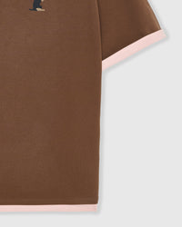 Detail of burgundy ringer trim at sleeve edge on brown cotton showing contrast stitching