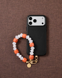 Clementine-orange bead phone strap styled on fabric, loved by thousands of STICKYZOO customers