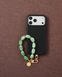 Phone with jade marble strap on brown fabric lifestyle flat-lay