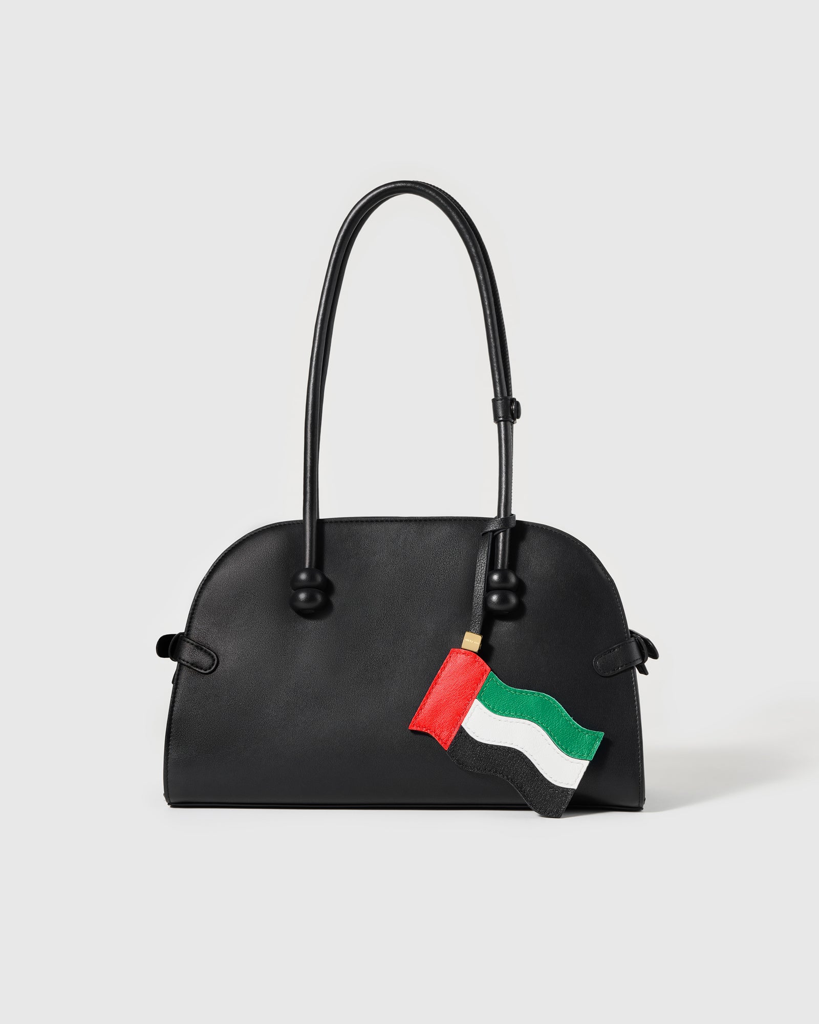 UAE flag leather charm clipped to black structured handbag showing waving flag movement by STICKYZOO