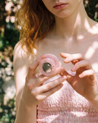 Person holding the pink acrylic-resin grip medallion outdoors in natural light