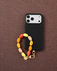Citrus mix agate stone phone strap with black phone on dark brown fabric lifestyle flat-lay