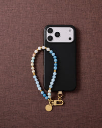 Phone with blue agate strap on dark brown fabric lifestyle flat-lay