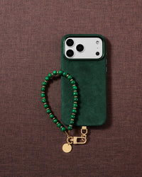 Deep green swirl beaded wrist strap styled in a lifestyle flat-lay on fabric, handmade bead by bead