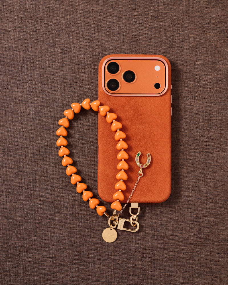 {Designed in Amsterdam} Tangerine heart beads and gold horseshoe charm phone strap styled flat-lay by STICKYZOO