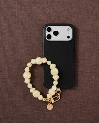 Phone with lemon glow strap on dark brown fabric lifestyle flat-lay