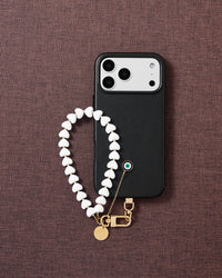 Flat-lay of frost eye amulet phone strap with engraved gold hardware and Phone Strap Card