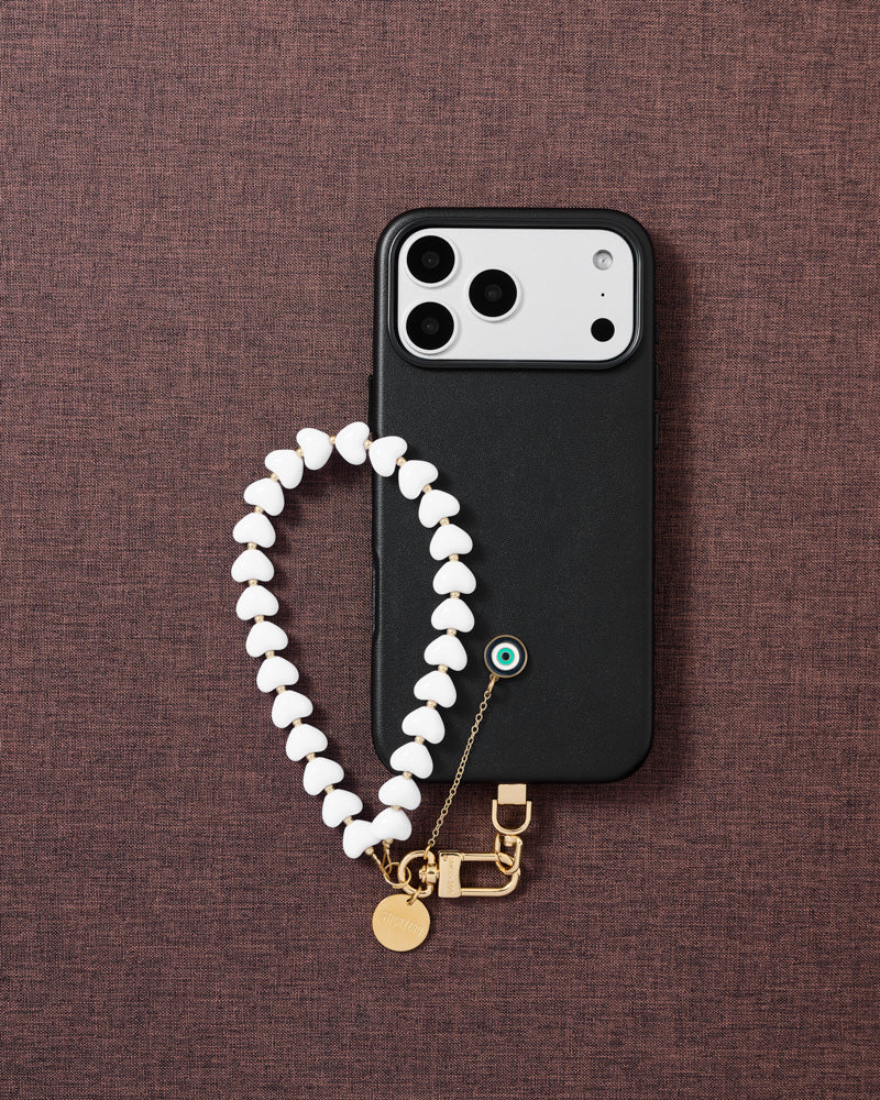 Flat-lay of frost eye amulet phone strap with engraved gold hardware and Phone Strap Card