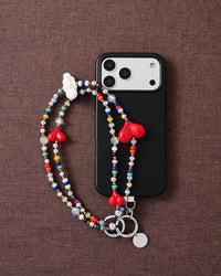 Triple heart multi-strand phone strap with black phone case on dark fabric lifestyle flat-lay